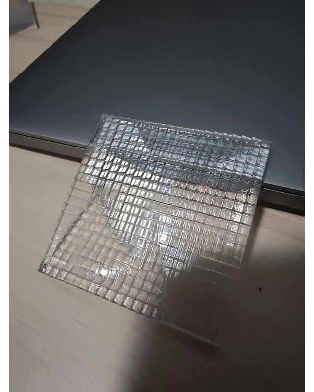 The lens resting on a desk, catching the light on its tilted facets