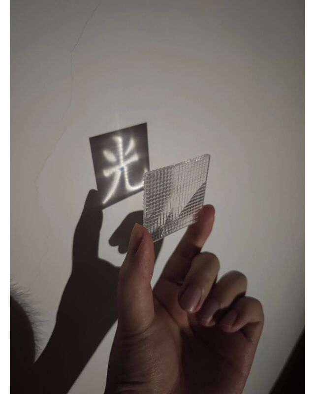 Another view of the lens projecting 光 onto a wall